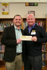 Dollar General's Mark Flowers is presenting a $50,000 check to principal Matthew Hull